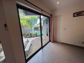 Ein Zimmer mit einer großen Schiebeglasdoor, die auf einen Außenbereich mit Holzterrasse und Pool führt.