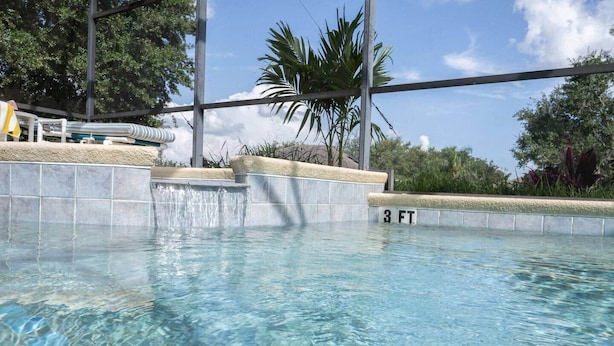 Ein klares Schwimmbecken mit Tiefenmarkierung von 3 Fuß, umgeben von einer gefliesten Terrasse und Palmen.