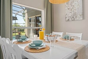A dining area with a table set for four, including plates, bowls, and glasses. - 5★ New 4BR 3BA - 3 mi to WDW, tropical Pool, Spa with all day sun, Tiki Gameroom (Four Corners)