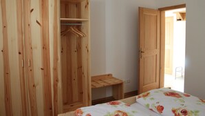 Een slaapkamer met een houten garderobe, een bed met bloemenbeddengoed en een klein houten tafeltje.