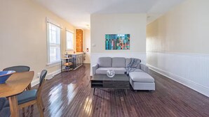 A living room with a sofa, coffee table, and dining area with chairs and a table. - 3-Bedroom in Downtown Columbus (Columbus)