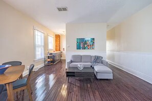 Ein Wohnzimmer mit einer Couch, einem Couchtisch und einem Essbereich mit Stühlen und Tisch.