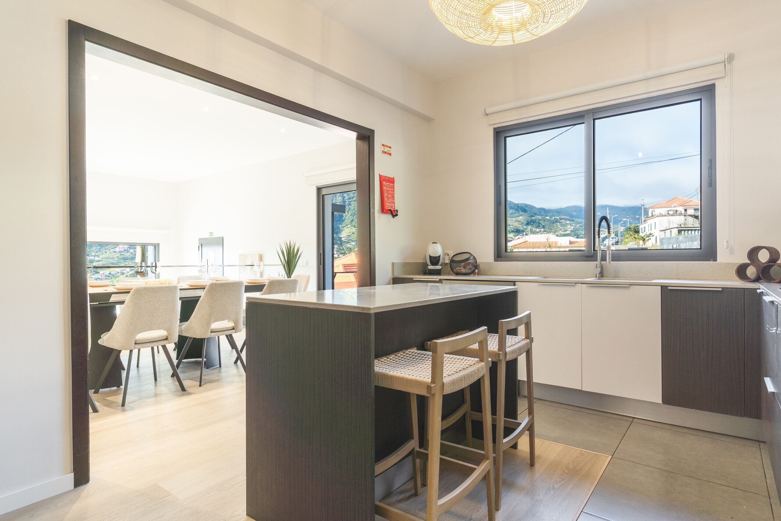 Une cuisine moderne dotée d’un grand îlot central, de tabourets de bar et offrant une vue sur la ville grâce à une grande fenêtre.
