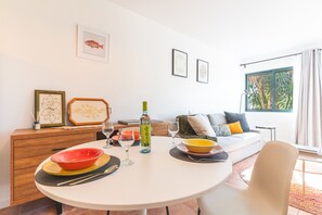 A dining area with a round table, a sofa, and a window with curtains. - Richelieu Apartment by Atlantic Holiday (Água de Pena)
