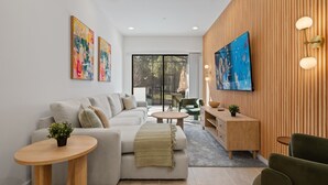 Ein modernes Wohnzimmer mit einer Couch, einem Couchtisch und einem an der Wand montierten Fernseher.