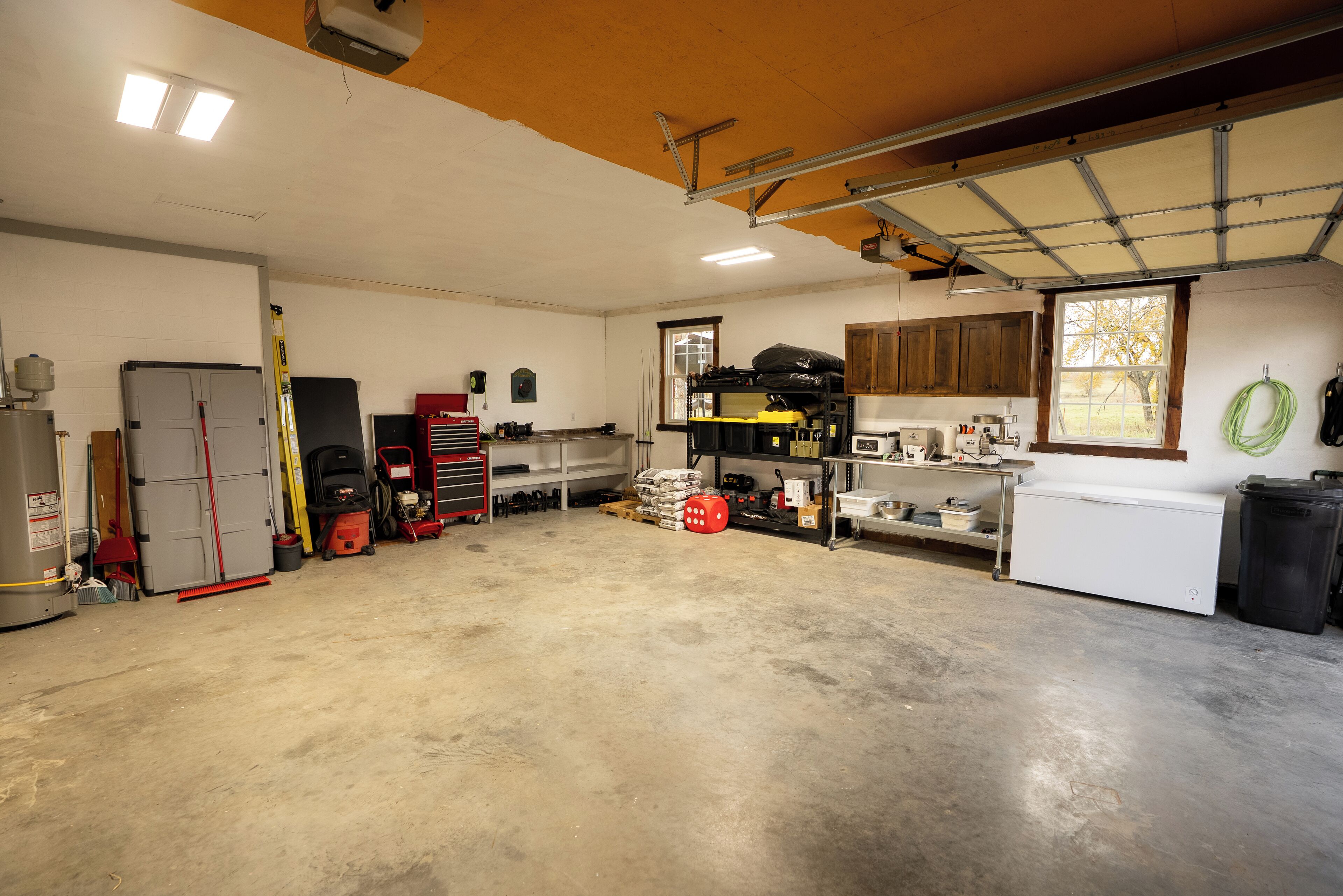 A spacious garage with a concrete floor, a large workbench, and various tools and equipment.