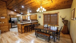 Interior de una cabaña de madera con comedor, cocina y una gran decoración de astas.