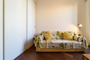 Ein Zimmer mit einer Couch an der Wand, einer Lampe und einem Holzboden.