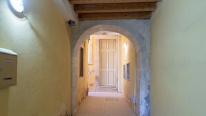 Un pasillo estrecho con un arco que da a una habitación con una puerta.