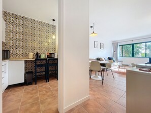 Une cuisine moderne avec un mur arrière décoré de motifs, un coin repas avec des chaises et une table, et une grande fenêtre offrant une vue dégagée.