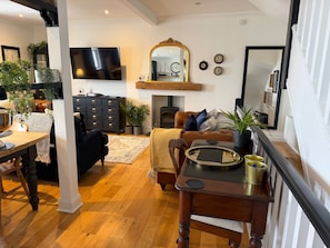 Un salon avec une cheminée, un téléviseur et un coin repas comprenant une table et des chaises.