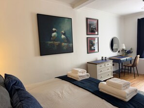 Une chambre à coucher comprenant un lit, un bureau, une chaise et des œuvres d’art accrochées aux murs.