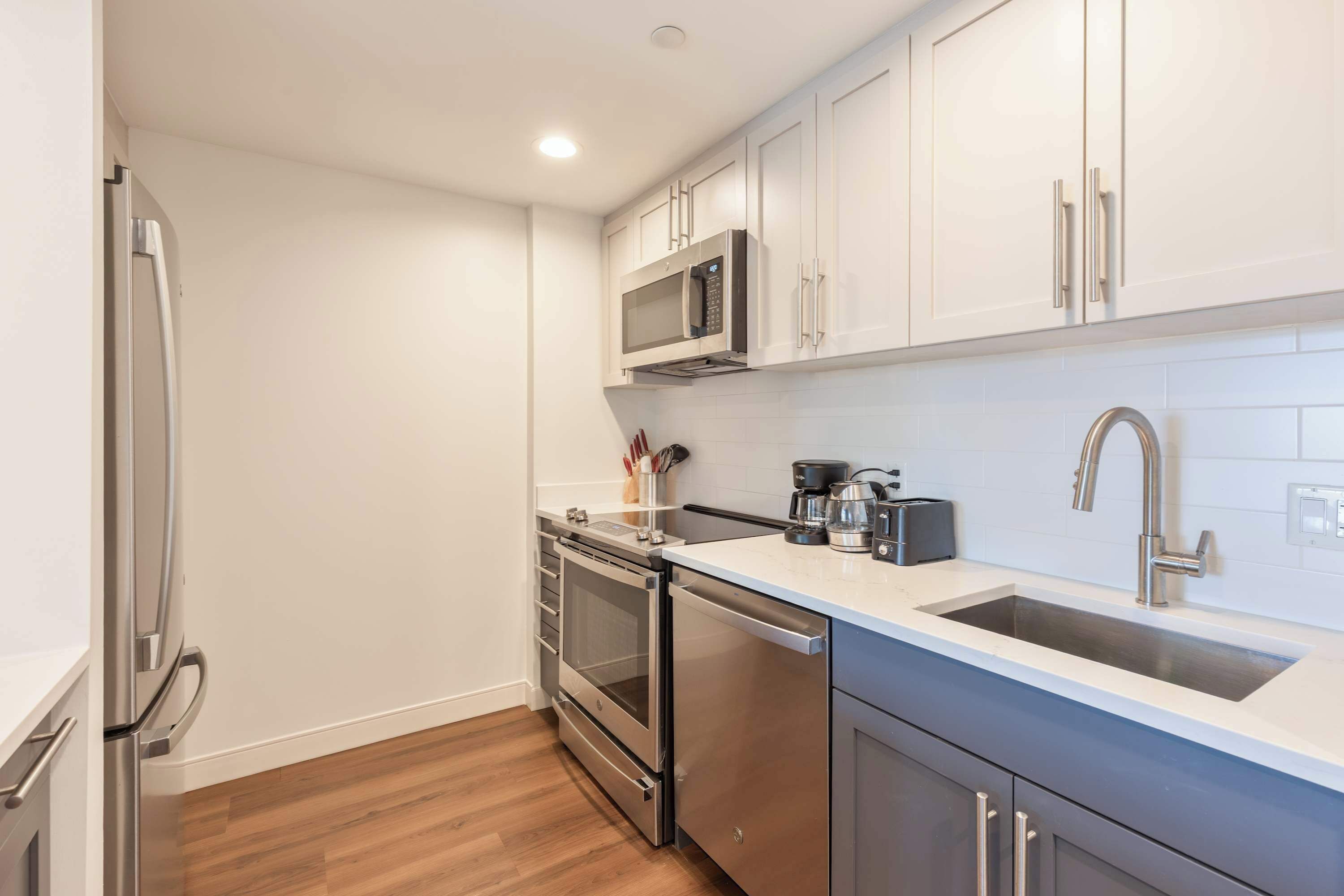 A modern kitchen with stainless steel appliances, white cabinetry, and a built-in microwave.
