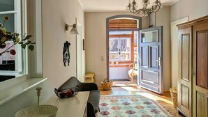 A hallway with a patterned rug, a dining area with a table and chairs, a basket on the table, and a door leading to an outdoor area. - Holiday Home Sommergrün with Garden (Nordwestuckermark)