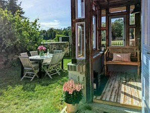 A patio with a table and chairs, a wooden bench, and a glass door leading to an outdoor area.