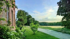 A riverside view with a brick building, lush greenery, and a clear sky. - Holiday Home Sommergrün with Garden (Nordwestuckermark)