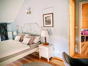 A bedroom with a bed, bedside lamps, a nightstand, a chair, and a wooden floor. - Himmelblau Loft with Garden – 1870 Uckermark (Nordwestuckermark)