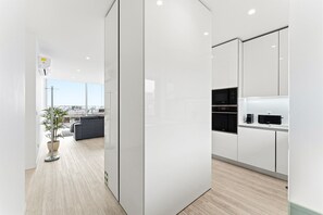 A modern kitchen with white cabinetry, a built-in oven, and a coffee maker. - GuestReady - Sunny Aveiro retreat (Aveiro)