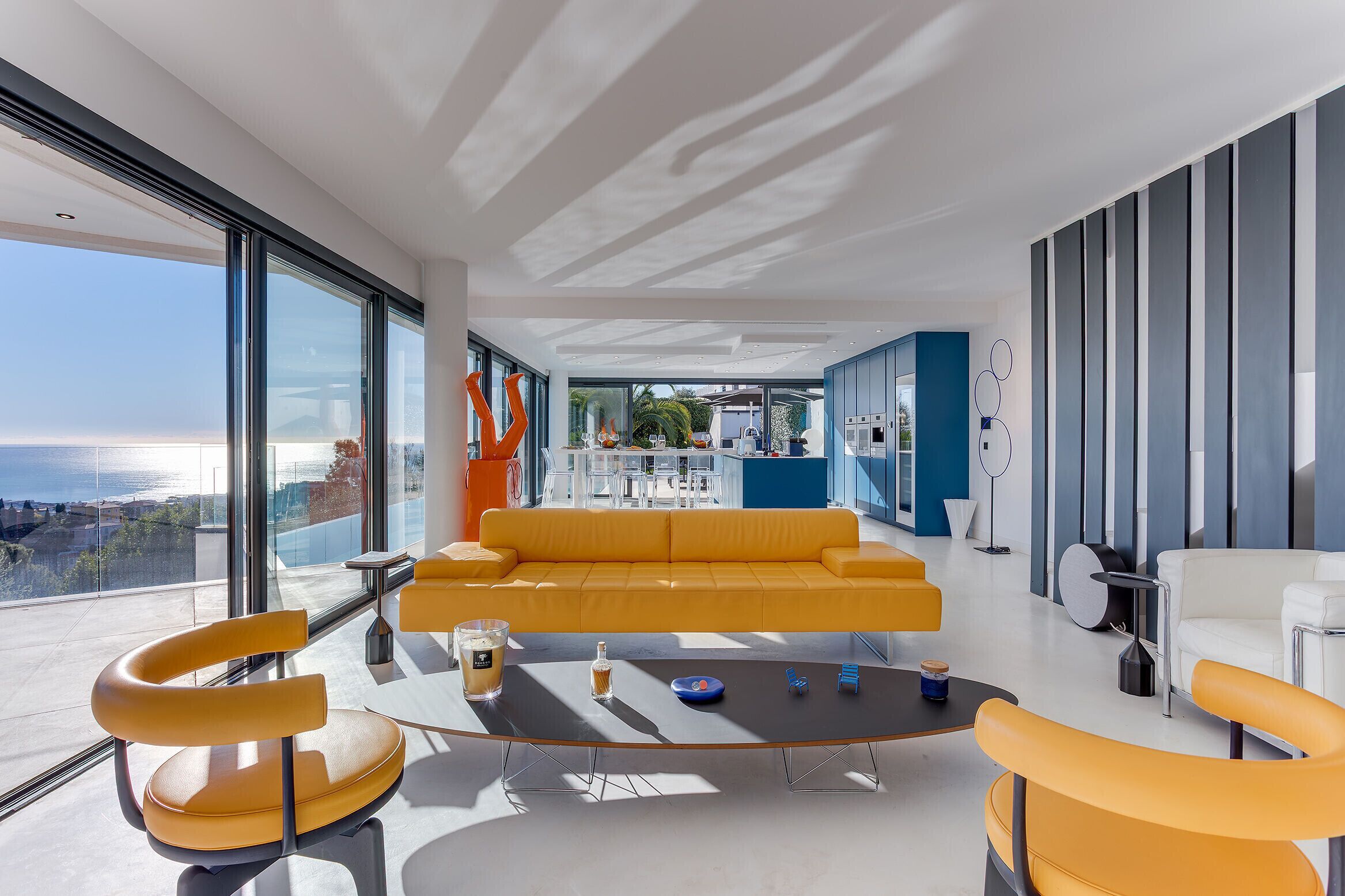 A modern living room with a yellow sofa, orange chairs, and a coffee table.