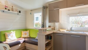 Um espaço de estar compacto com cozinha compacta, sofá verde e janela decorada com bicicleta.
