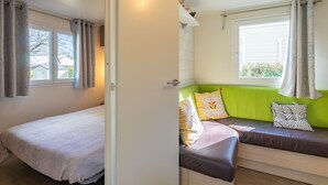 Um quarto com uma cama, um sofá verde e uma janela com cortinas.