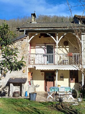 A two-story building with a balcony, a front door, and a small porch area with outdoor furniture. - Traditional Mountain House with View, Private Terrace and Garden in Ercé (Ercé)