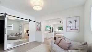 Un salon moderne avec un canapé, une porte coulissante à miroir et des œuvres d’art accrochées aux murs.
