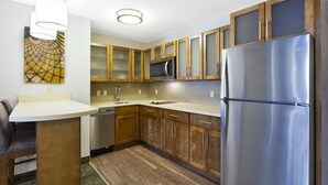 A modern kitchen with wooden cabinets, a stainless steel refrigerator, and a microwave.