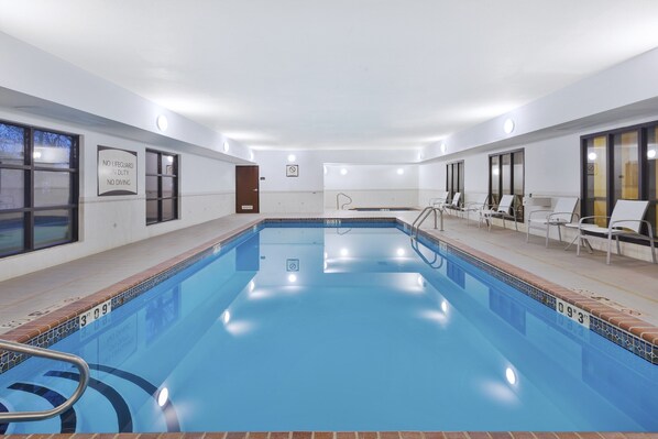 A swimming pool with a tiled edge, a lifeguard sign, and a door.