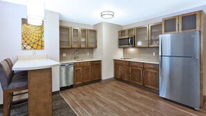 A modern kitchen with wooden cabinets, stainless steel appliances, and a bar area. - 1BR Suite w/ Fireplace & Kitchen + Breakfast | Near Mizzou (Columbia)