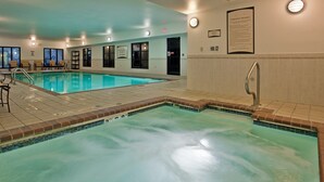 An indoor swimming pool with clear water, a tiled deck, and a sign detailing spa rules.