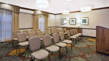 A conference room with rows of chairs, a podium, and a carpet with a leaf pattern.