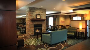 A lobby with a stone fireplace, seating area, and a dining section.