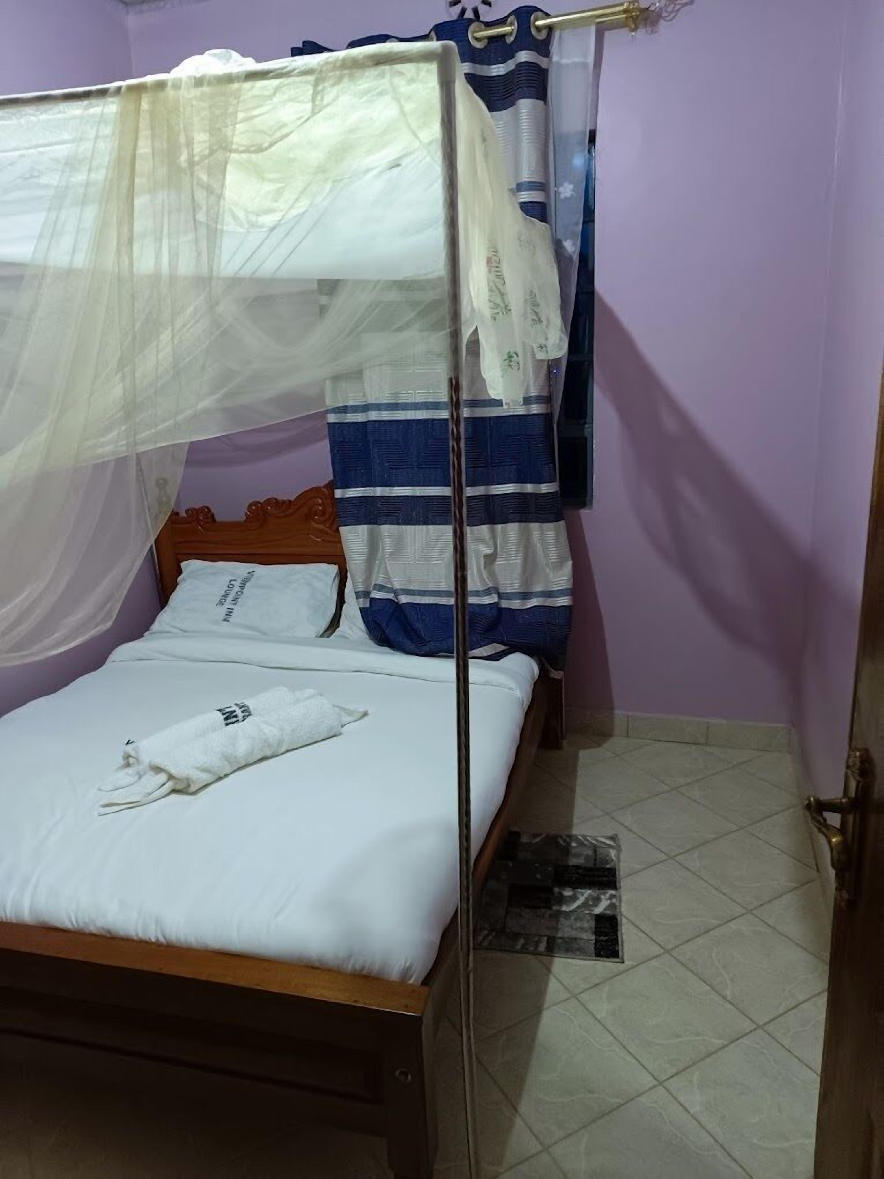 A single bed with a canopy, a pillow, and a rolled towel.