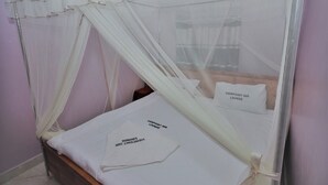 Un lit doté d’un baldaquin blanc et de coussins sur lesquels est inscrit « POINT DE VUE SUR LE SALON ».