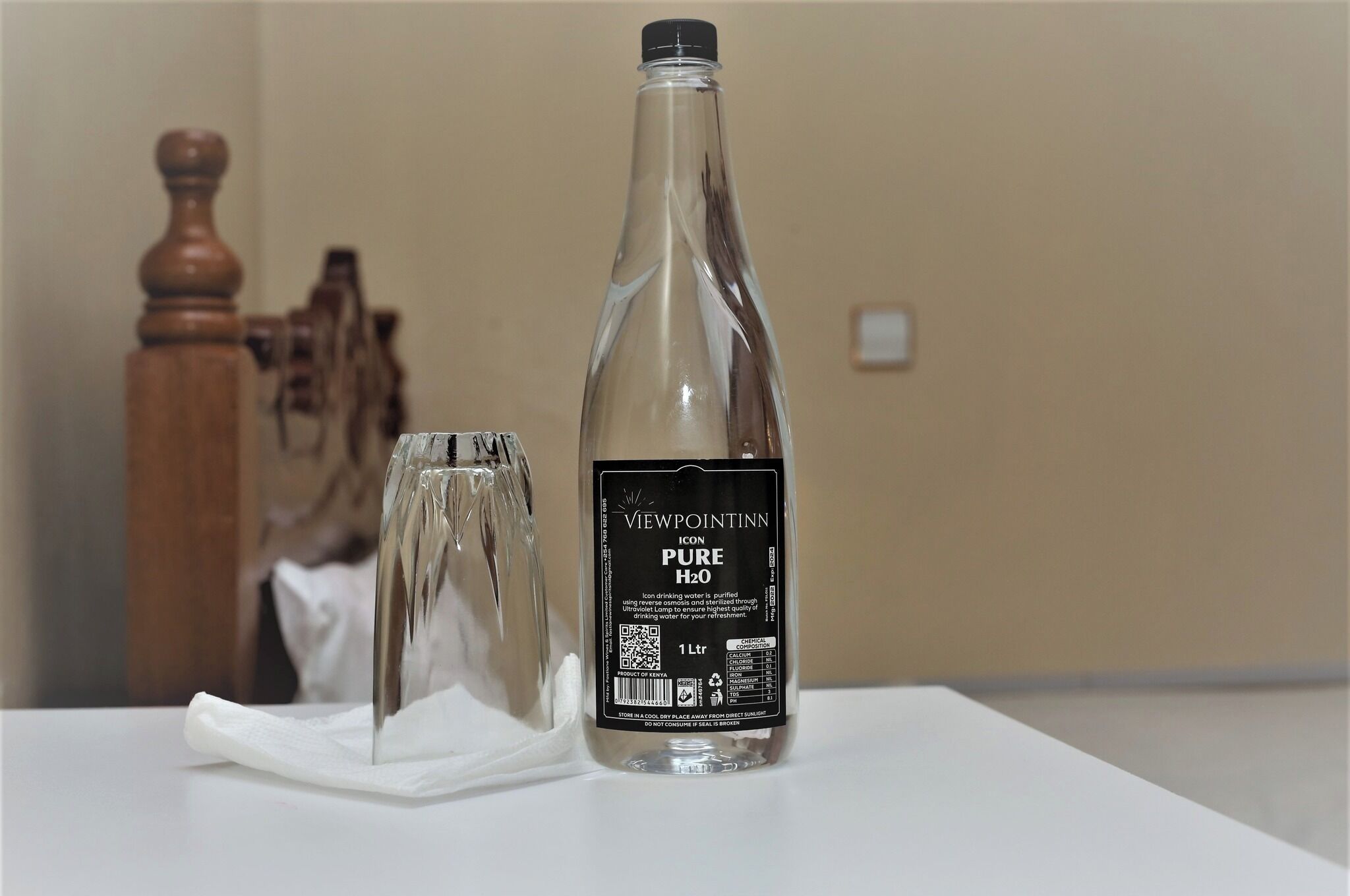 Una botella de agua Viewpointinn ICON Pure H2O sobre una mesa blanca, con un vaso transparente a su lado.