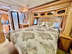 Ein Schlafzimmer mit einem großen Bett, einem Schminktisch mit Spiegel und Holzschränken darüber.