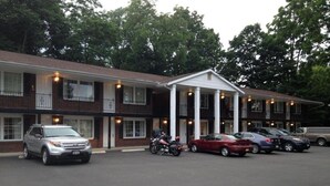 A motel with a central entrance, multiple parking spaces, and a brick facade.