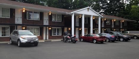 A motel with a central entrance, multiple parking spaces, and a brick facade.
