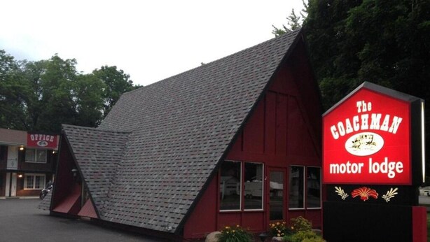 A red building with a sloped roof and a sign that reads "The Coachman Motor Lodge."