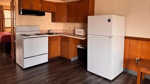A compact kitchen with wooden cabinets, a white stove, and a refrigerator.