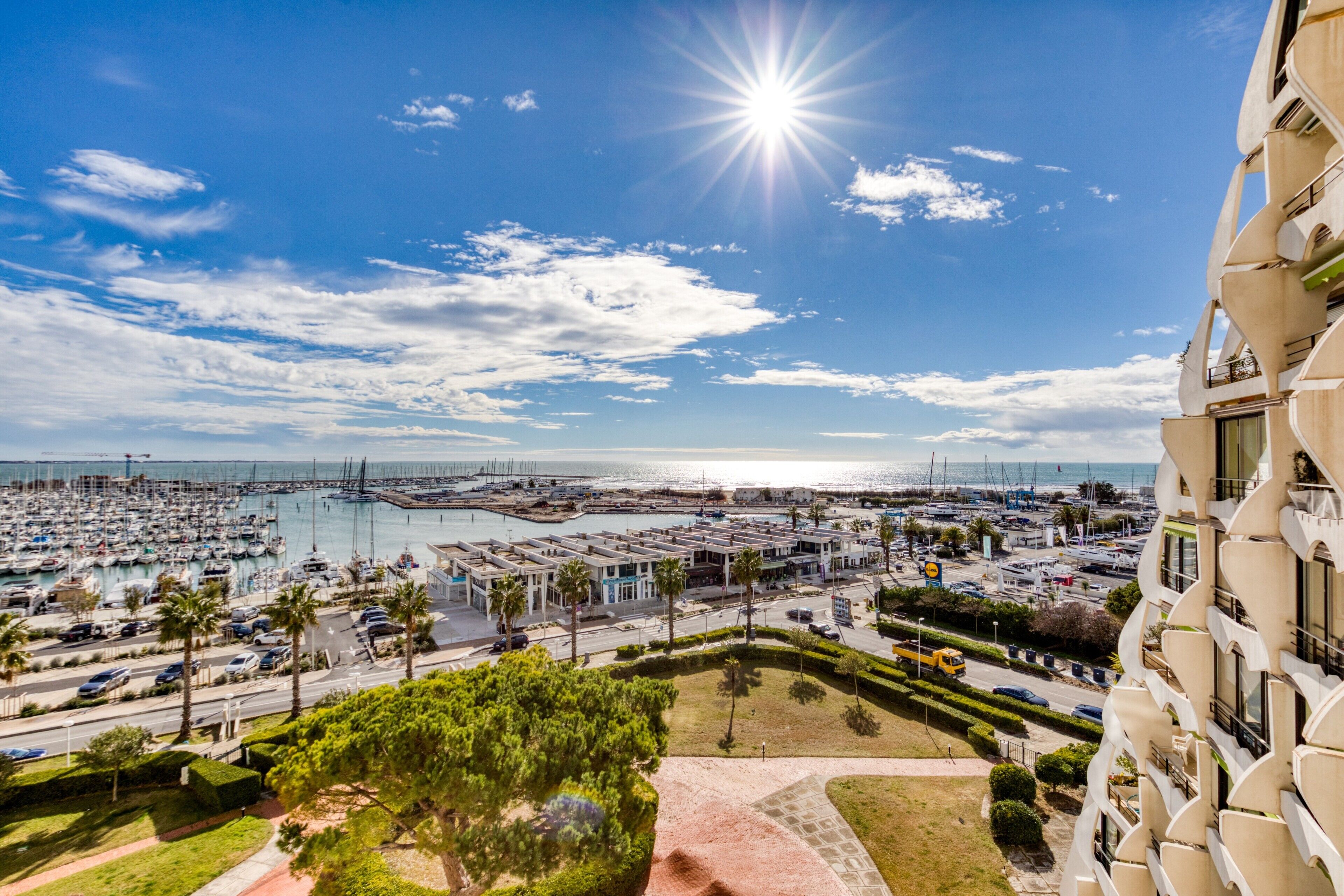 Un port de plaisance avec des bateaux, un ciel dégagé et un immeuble doté de balcons.