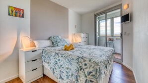 A bedroom with a bed, bedside tables, a TV, and a balcony with a view. - The Splendid Grande Pyramide with Sea View, Wi-Fi, and Air Conditioning (La Grande-Motte)