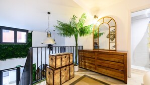 Eine Treppe mit Blick auf ein Gebäude, eine Holzkommode, ein Spiegel und ein Blumentopf.