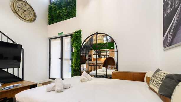 Ein Hotelzimmer mit einem Bett, einem Fernseher, einer Uhr und einer grünen Wanddekoration.