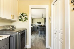 A laundry area with a washing machine, a dryer, and a wall-mounted wreath. - Morrison’s Beach Road Island Retreat (Georgetown)