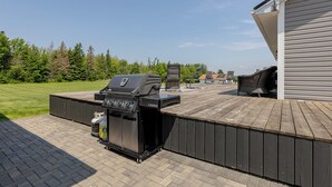 An outdoor patio with a grill, a barbecue table, and a covered seating area.