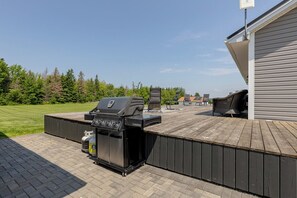 An outdoor patio with a grill, a barbecue table, and a covered seating area.
