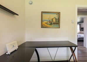 Ein Zimmer mit einem schwarzen Tisch, einem Gemälde einer Küstenszene und einem weißen Gerät auf dem Tisch.
