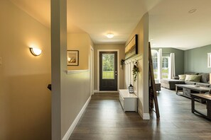 A hallway with a door, a bench, and a seating area with a couch and coffee table. - Morrison’s Beach Road Island Retreat (Georgetown)